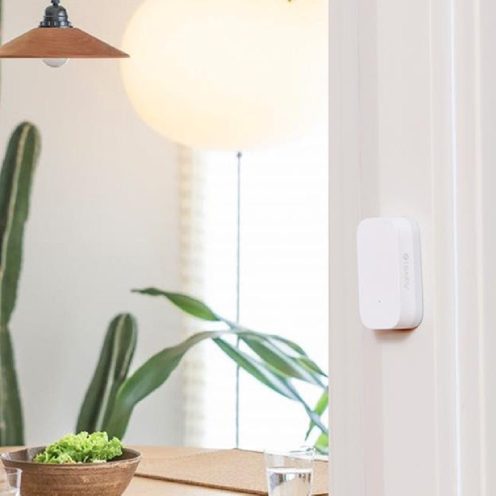Xiaomi Aqara smart door sensor installed on door frame with modern home background