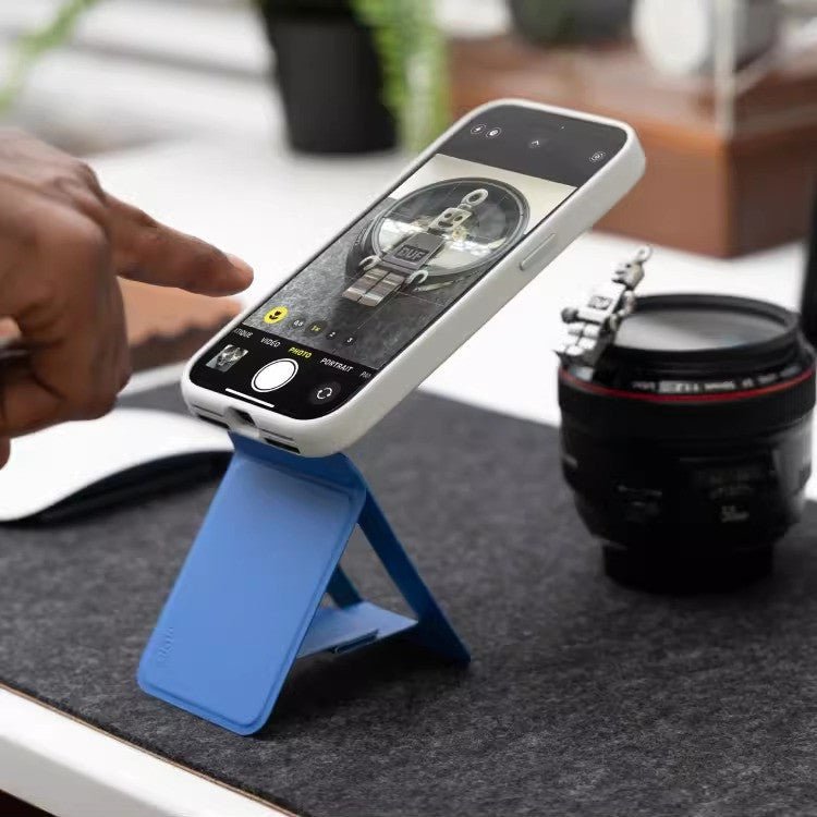 Multifunctional magnetic mobile phone holder with blue foldable stand supporting white smartphone.