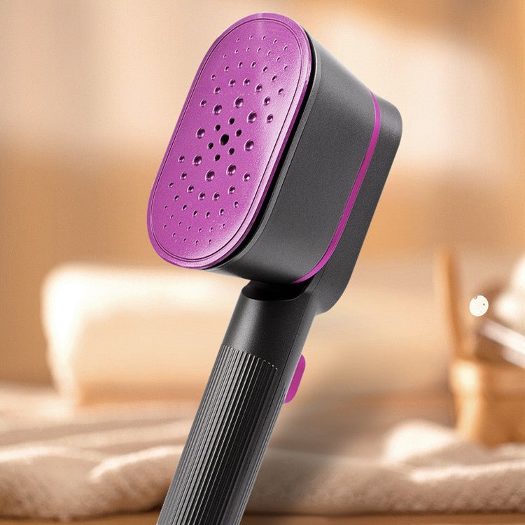 Household Small Portable Steamer  in black and pink used to steam a beige blazer sleeve. Compact vacuum steamer ideal for home use.